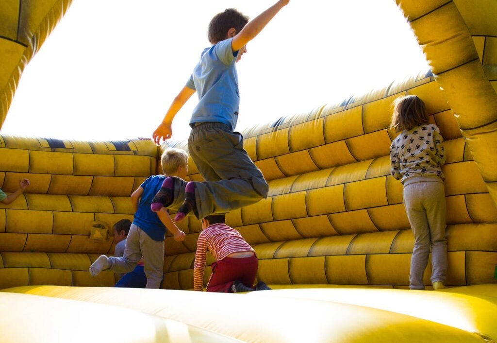 Kids enjoying a fun time bouncing in a vibrant inflatable castle outdoors.